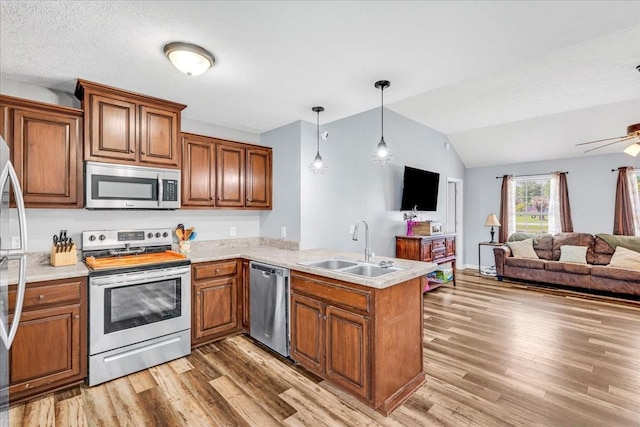 890 Akersville Rd, Lafayette, TN 37083 - kitchen featuring stainless steel appliances, a sink, open floor plan, a peninsula, and brown cabinetry
