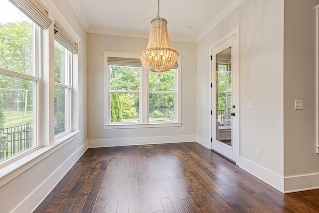 unfurnished dining area with plenty of natural light, a chandelier, ornamental molding, and dark wood finished floors