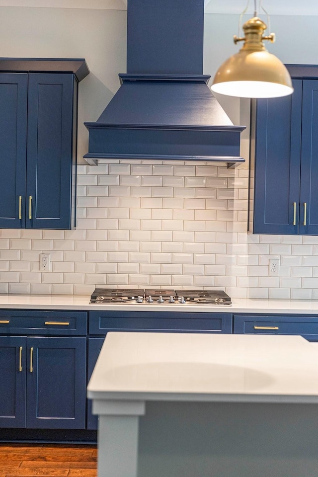 kitchen with blue cabinets, premium range hood, and stainless steel gas stovetop