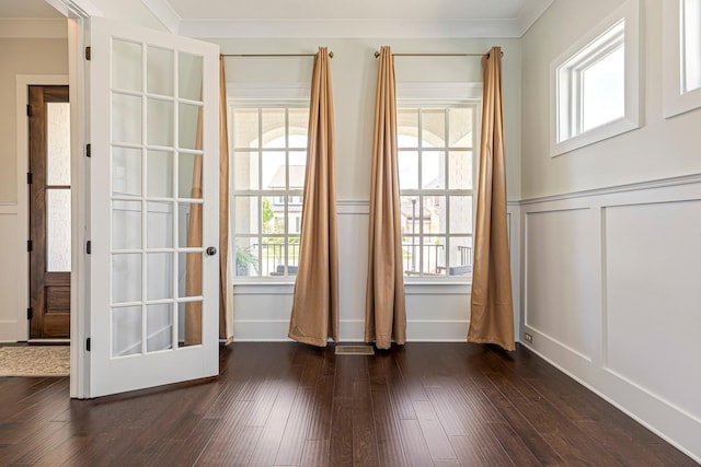 doorway featuring a decorative wall, a wainscoted wall, healthy amount of natural light, and dark wood-style flooring