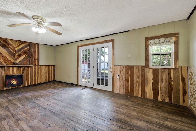 159 Clover St, Granville, TN 38564 - unfurnished living room with wood walls, a textured ceiling, hardwood / wood-style floors, healthy amount of natural light, and a warm lit fireplace