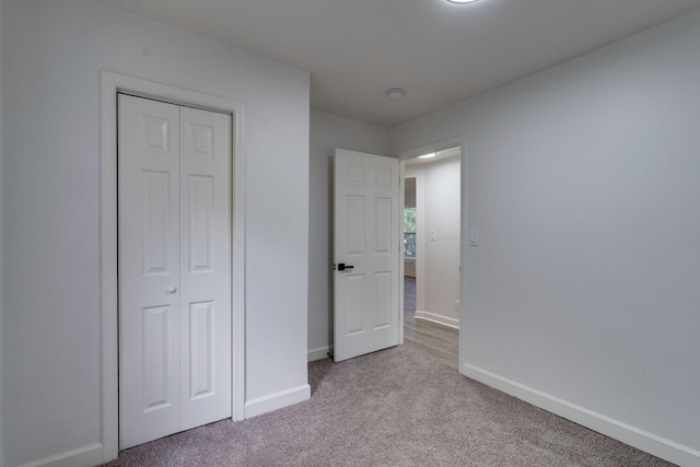 unfurnished bedroom with baseboards, carpet flooring, and a closet