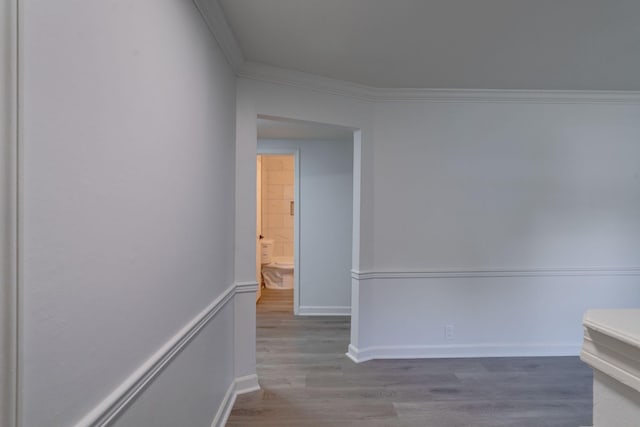 corridor featuring ornamental molding, wood finished floors, and baseboards