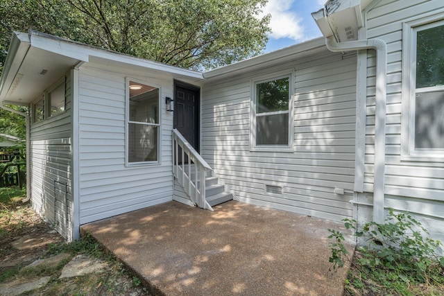 view of exterior entry featuring a patio area and crawl space