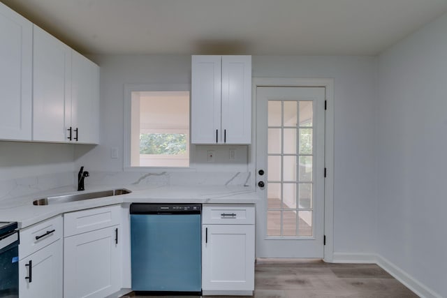 kitchen featuring dishwashing machine, a sink, light wood finished floors, light stone countertops, and white cabinetry