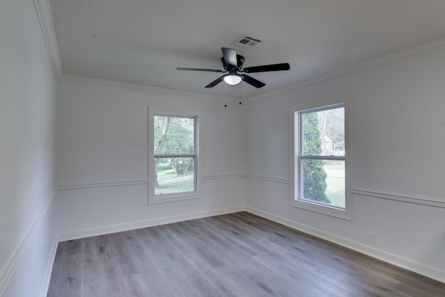 spare room featuring ornamental molding, plenty of natural light, wood finished floors, ceiling fan, and baseboards
