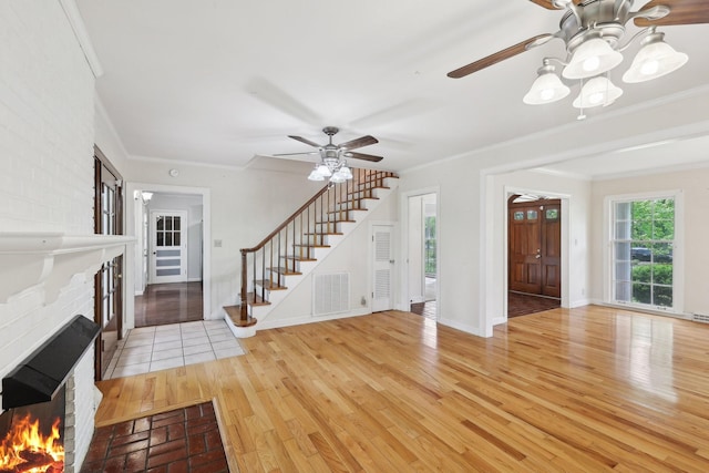 111 Lois Ln, Clarksville, TN 37043 - foyer featuring a brick fireplace, stairway, crown molding, a ceiling fan, and light wood finished floors
