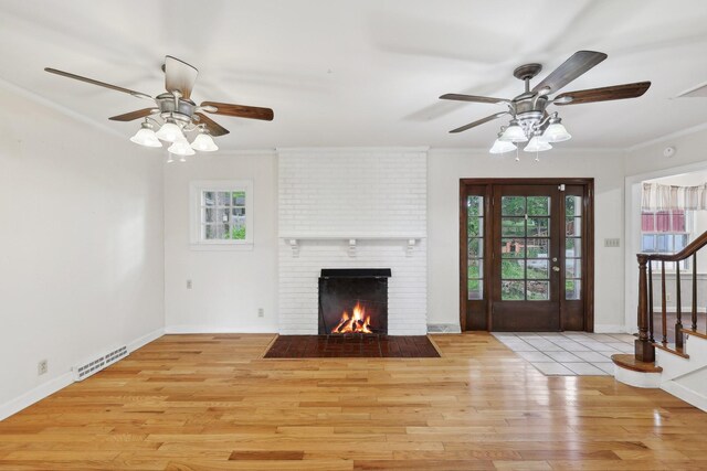 111 Lois Ln, Clarksville, TN 37043 - unfurnished living room featuring a ceiling fan, crown molding, stairs, a brick fireplace, and light wood-style floors