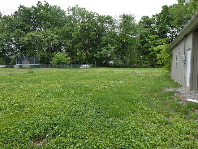 view of yard featuring a trampoline and view of wooded area
