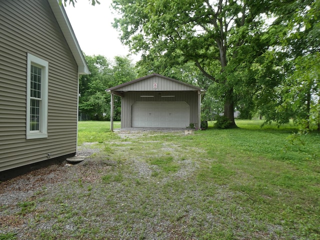 view of grassy yard with a garage, an outdoor structure, and driveway