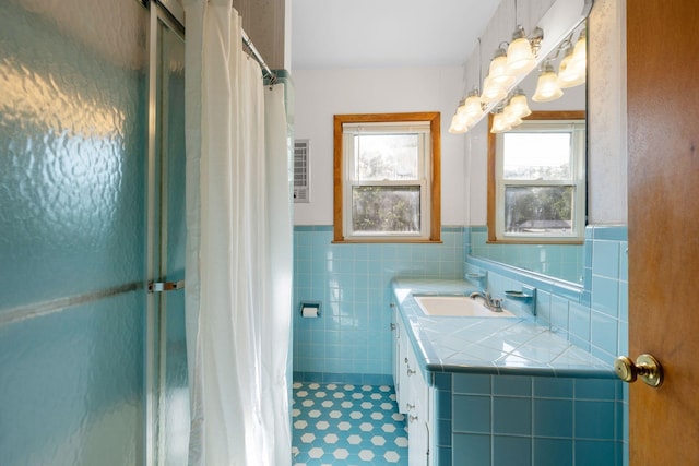 full bath featuring tile patterned flooring, tile walls, a shower stall, a wainscoted wall, and vanity