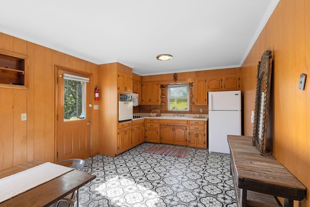 kitchen with white appliances, a sink, light countertops, brown cabinetry, and crown molding