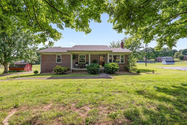 ranch-style home with a chimney, covered porch, a front lawn, and brick siding