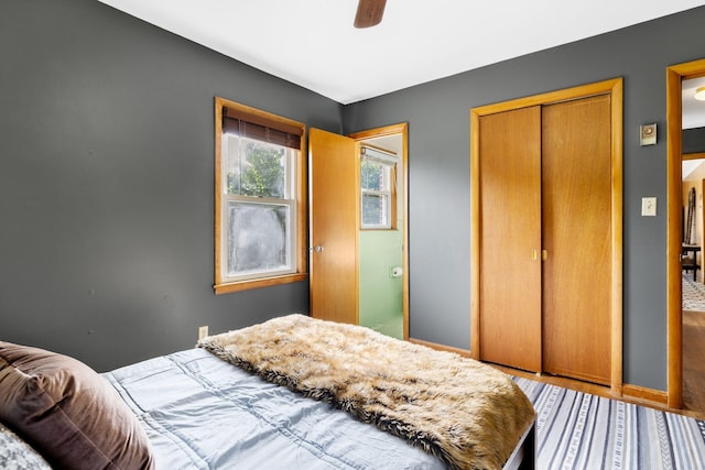 bedroom featuring a closet, wood finished floors, baseboards, and ceiling fan
