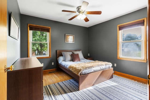 bedroom with light wood-type flooring, baseboards, and a ceiling fan