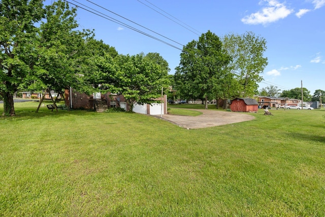 view of grassy yard with an outdoor structure, a shed, a garage, and driveway