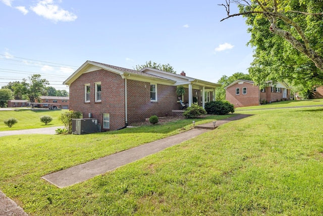 view of property exterior with brick siding, a yard, and a chimney