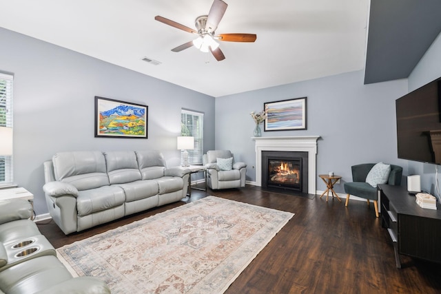 living room with ceiling fan, wood finished floors, plenty of natural light, and a fireplace with flush hearth