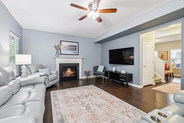 living area with wood finished floors, ceiling fan, a fireplace with flush hearth, and baseboards