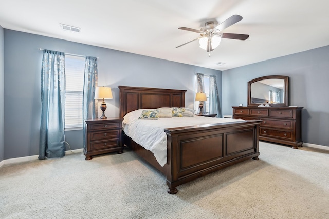 bedroom featuring multiple windows, baseboards, light colored carpet, and a ceiling fan