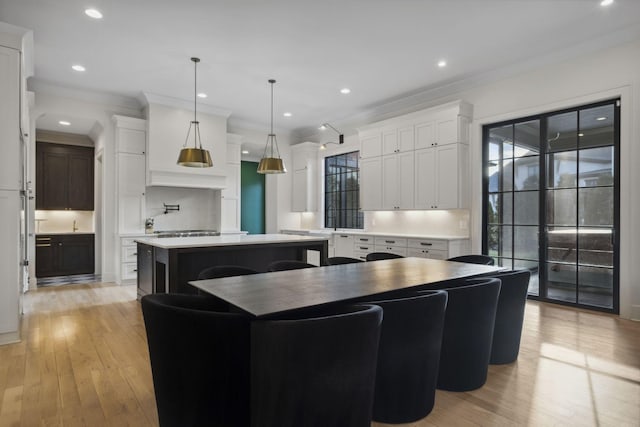 kitchen featuring a kitchen island, white cabinetry, light wood-style floors, crown molding, and recessed lighting