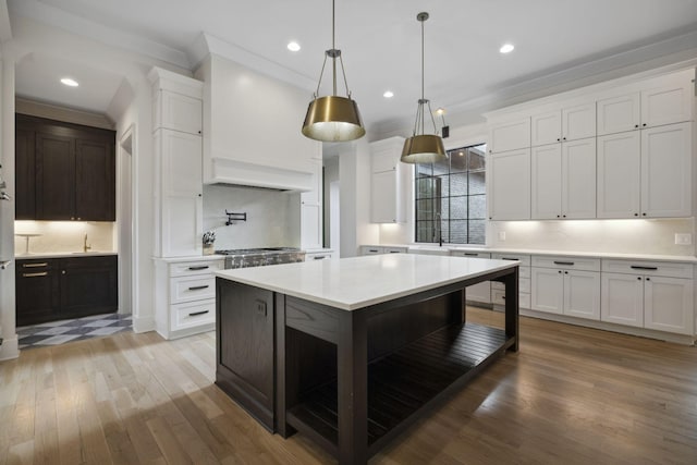 kitchen with light countertops, wood finished floors, white cabinets, recessed lighting, and pendant lighting