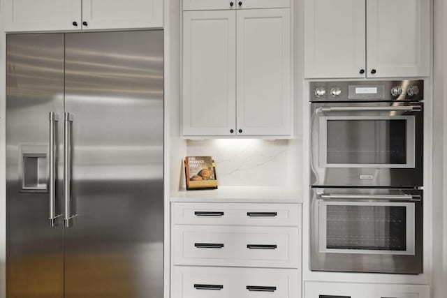 kitchen featuring appliances with stainless steel finishes, light countertops, white cabinetry, and tasteful backsplash