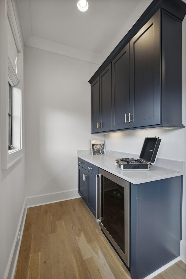 bar with beverage cooler, light wood-type flooring, and baseboards