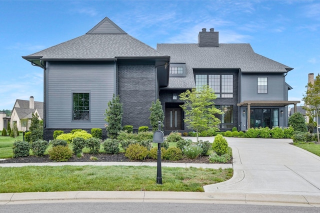 view of front facade featuring a chimney and a shingled roof