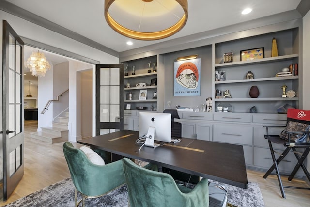 office with built in features, light wood-type flooring, and a chandelier