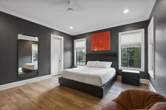 bedroom featuring multiple windows, wood finished floors, baseboards, recessed lighting, and crown molding