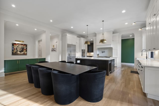 kitchen featuring appliances with stainless steel finishes, light countertops, a kitchen island, ornamental molding, and light wood-style flooring