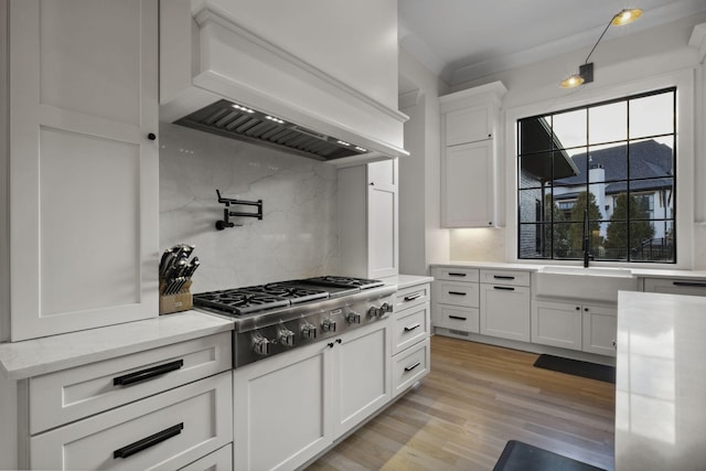 kitchen with premium range hood, stainless steel gas cooktop, decorative backsplash, and white cabinets