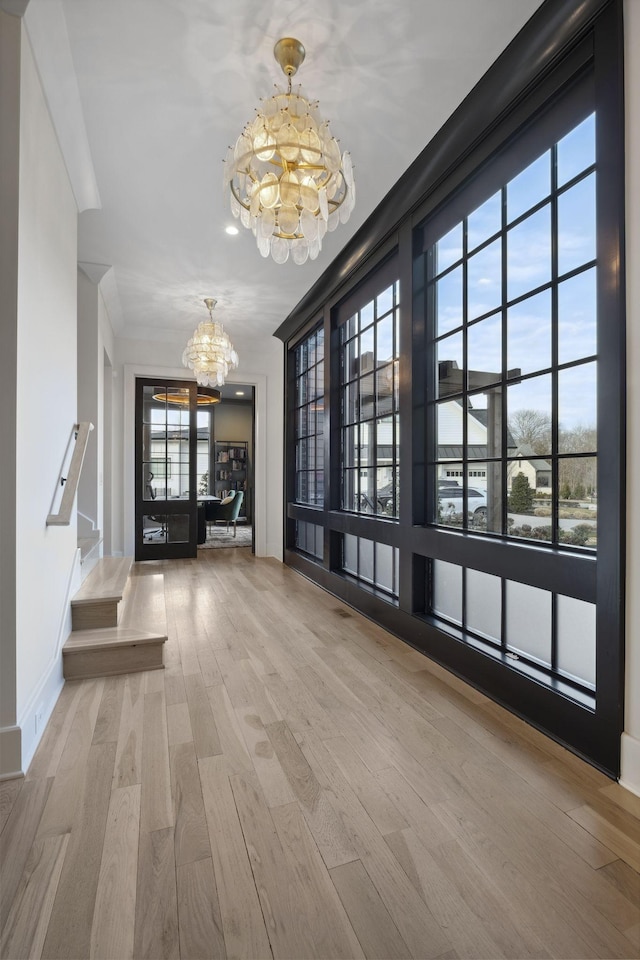 entrance foyer with a chandelier, wood finished floors, and baseboards