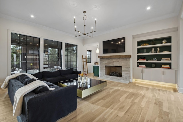 living area with healthy amount of natural light, light wood-type flooring, a fireplace, crown molding, and a chandelier