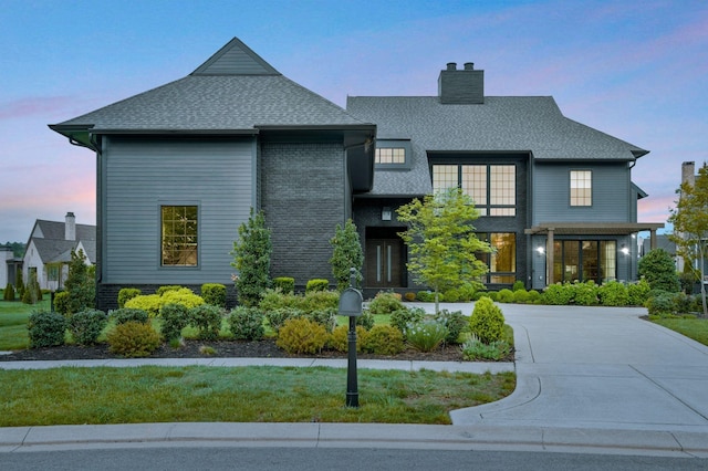 view of front of house with a chimney, a shingled roof, and a front yard
