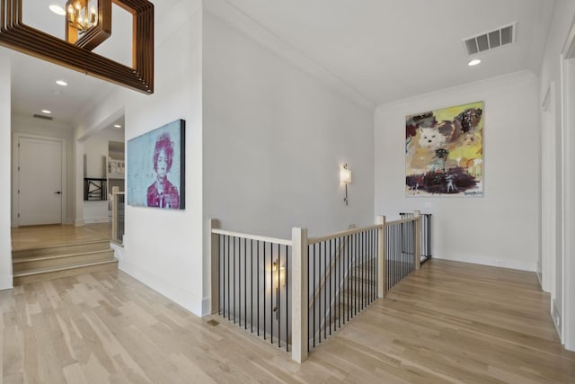 corridor with wood finished floors, ornamental molding, recessed lighting, baseboards, and an upstairs landing