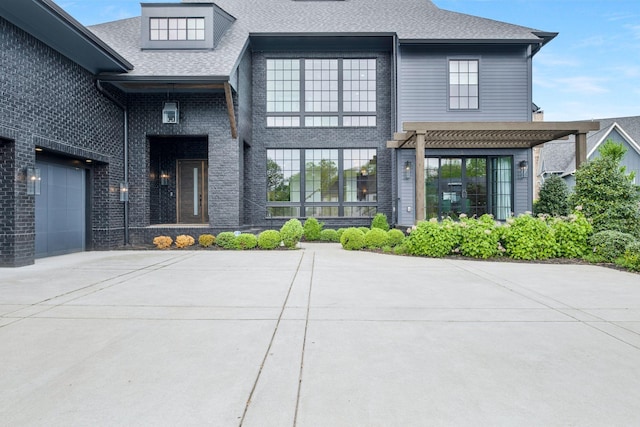 view of exterior entry with roof with shingles, concrete driveway, and brick siding