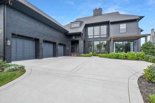 view of front of house with a chimney, driveway, brick siding, and a shingled roof