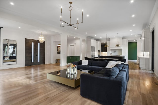 living area with a chandelier, light wood-style floors, ornamental molding, recessed lighting, and baseboards