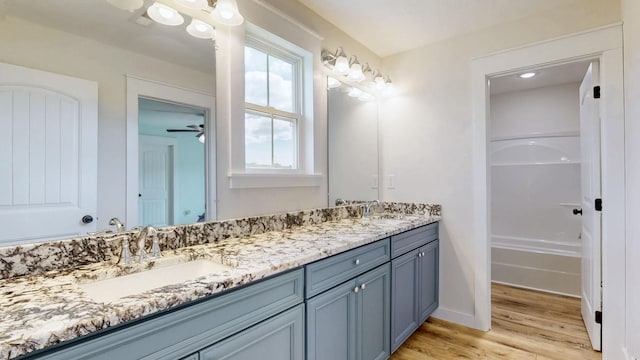 548 Buddy Rd, Burns, TN 37029 - bathroom with wood finished floors, double vanity, a bathtub, baseboards, and a ceiling fan
