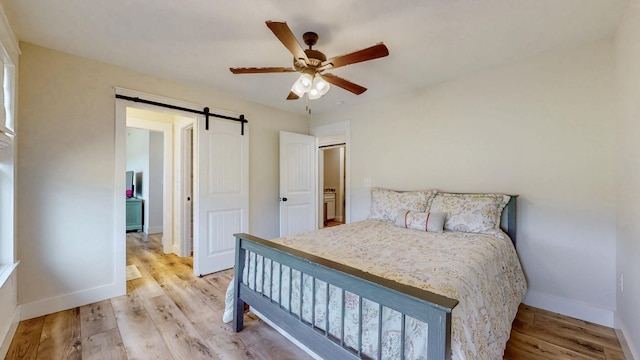 548 Buddy Rd, Burns, TN 37029 - bedroom with light wood-type flooring, baseboards, a barn door, and ceiling fan