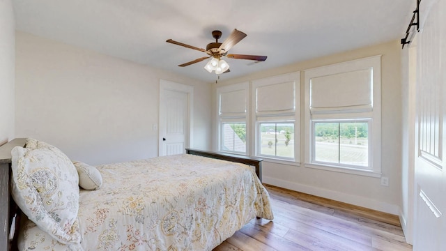 548 Buddy Rd, Burns, TN 37029 - bedroom with multiple windows, baseboards, light wood-style flooring, and a barn door