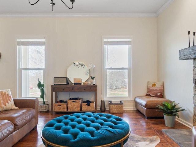 living area featuring wood finished floors, crown molding, baseboards, and a chandelier