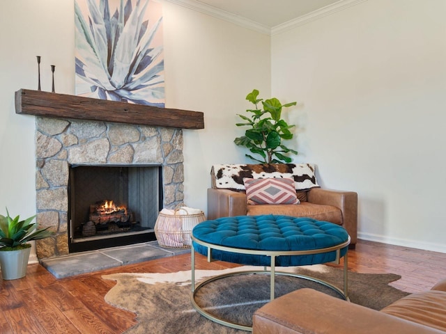 living area featuring wood finished floors, baseboards, ornamental molding, and a fireplace