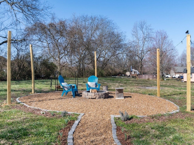 view of grassy yard with a fire pit and view of scattered trees