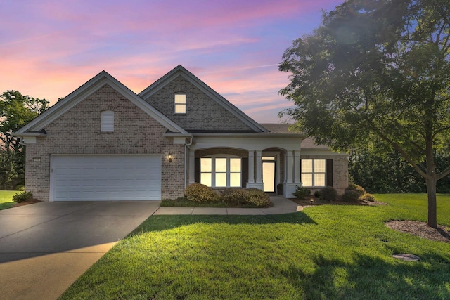 traditional home featuring brick siding, driveway, a lawn, and an attached garage