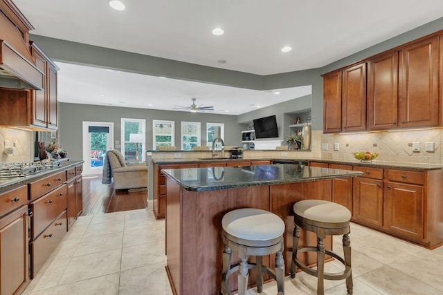 kitchen featuring a peninsula, recessed lighting, decorative backsplash, a sink, and stainless steel gas cooktop