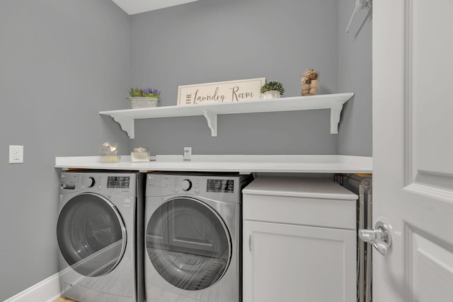 clothes washing area featuring washer and clothes dryer and baseboards
