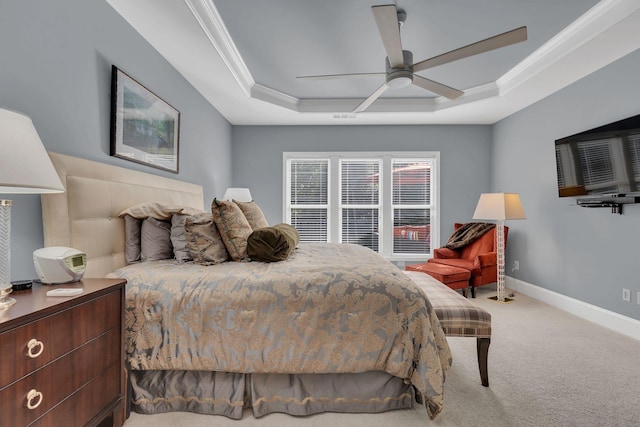 bedroom featuring a tray ceiling, crown molding, carpet floors, baseboards, and a ceiling fan